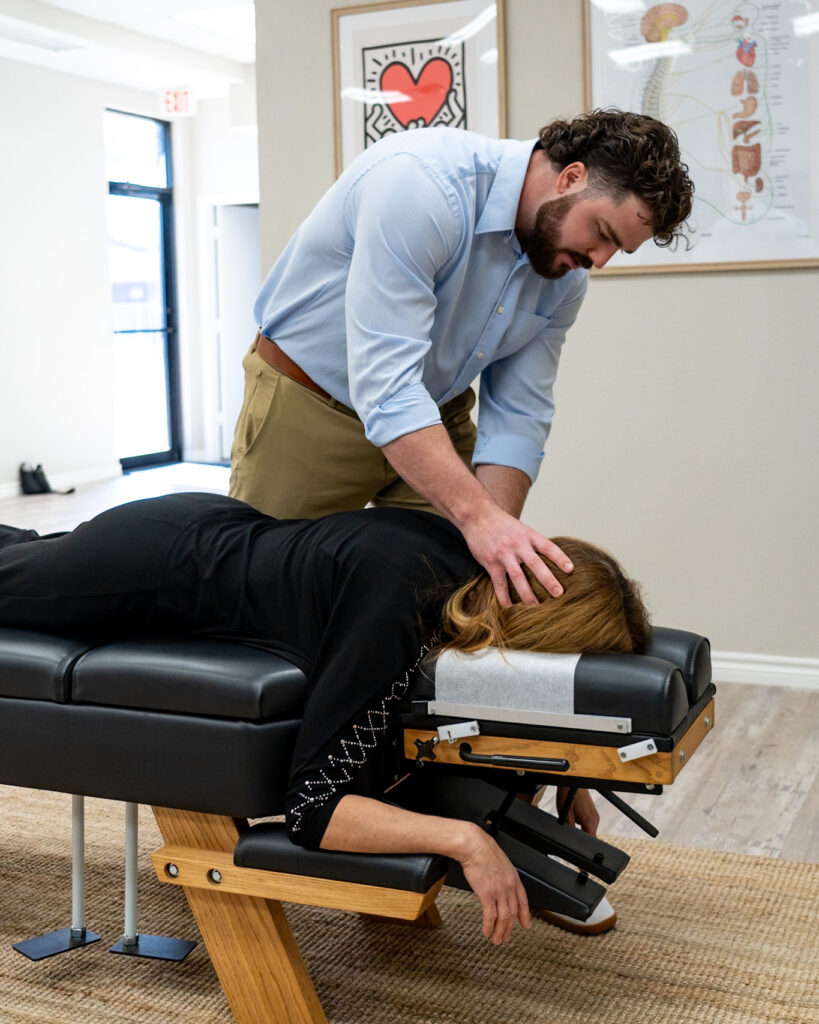 Adult chiropractor in Plano TX performing gentle neck adjustment to relieve chronic pain and support nervous system function