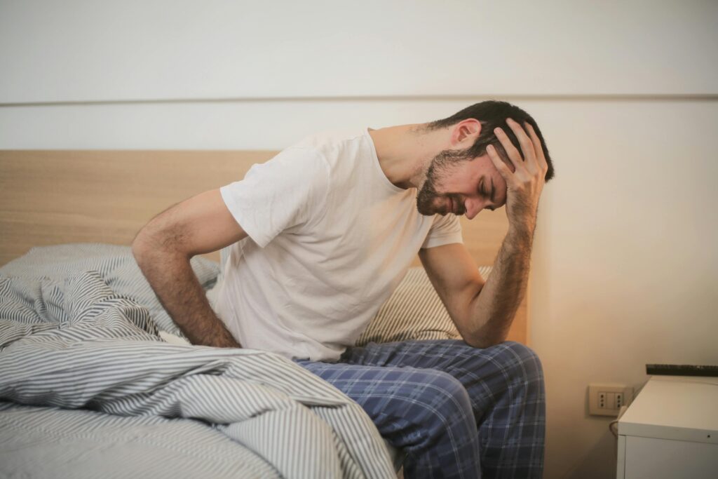 man experiencing migraine pain, holding head in discomfort