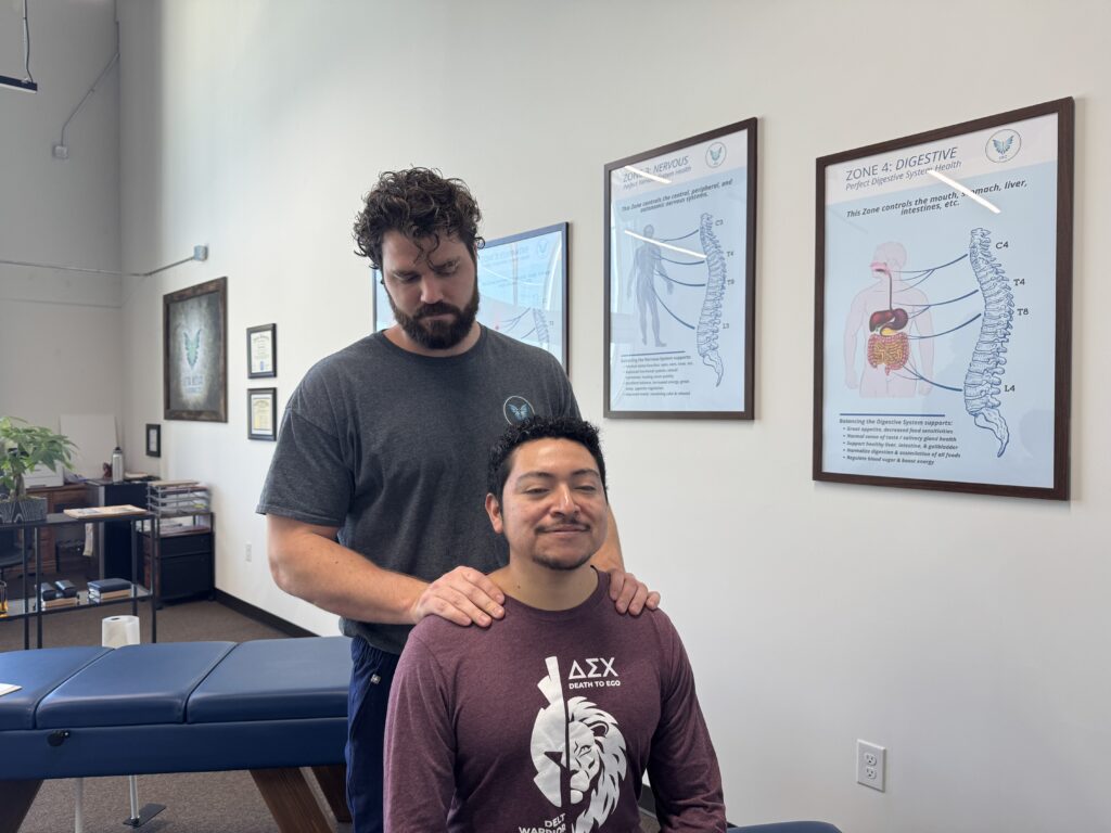 Chiropractor performing gentle neck adjustment on a smiling patient during anxiety-focused care in Plano