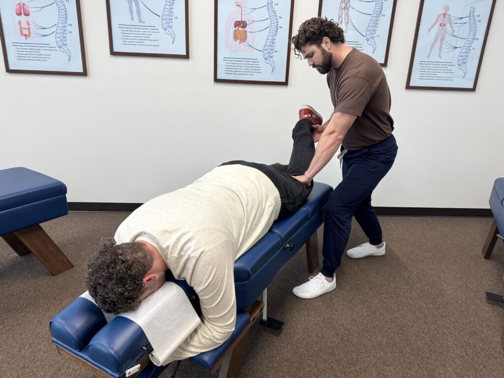 Chiropractor in Plano performing a therapeutic leg adjustment on a patient to help relieve bursitis pain and improve joint mobility