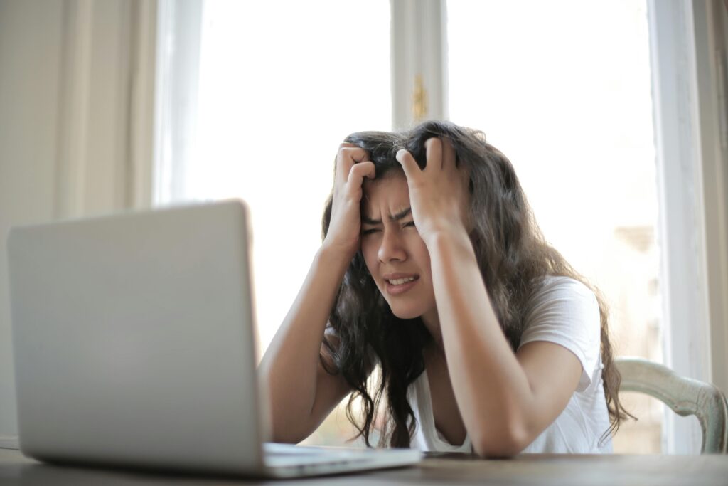 Stressed woman experiencing tension headache while working on laptop