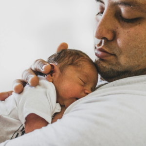 Father holding newborn baby receiving gentle chiropractic care at Vita Nova Chiropractic in Plano, TX for infant wellness