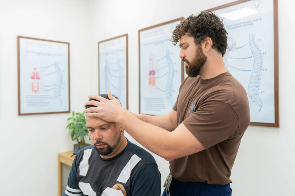Dr. Korrin Taylor places his hands on a seated patient's head during an examination.
