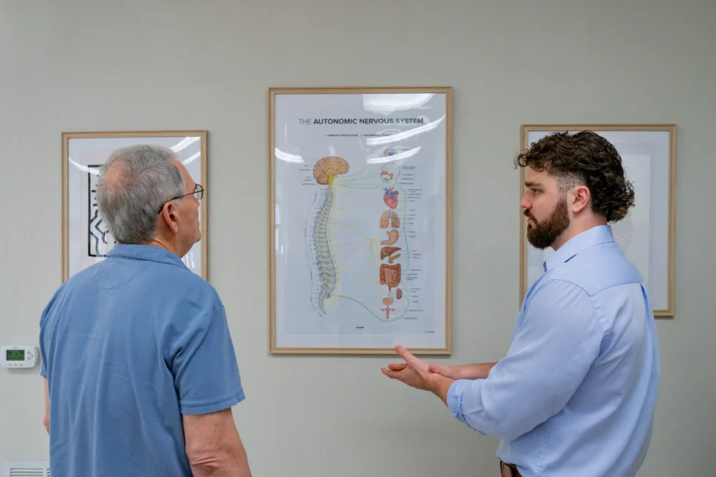 Dr. Korrin Taylor discusses an autonomic nervous system wall chart with a patient in his office.