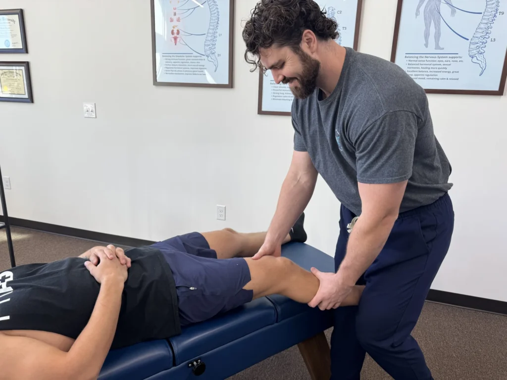 Dr. Korrin Taylor examines a patient's knee and leg on an adjusting table.