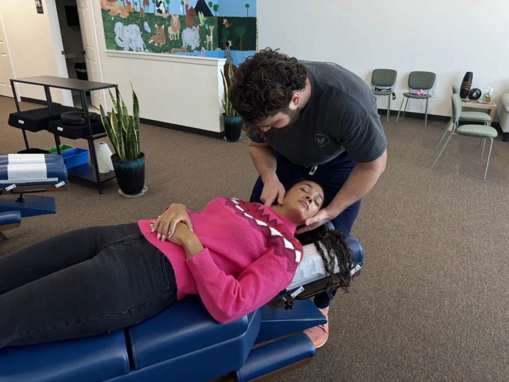 Dr. Korrin Taylor examining the neck of a patient lying on a blue adjustment table.