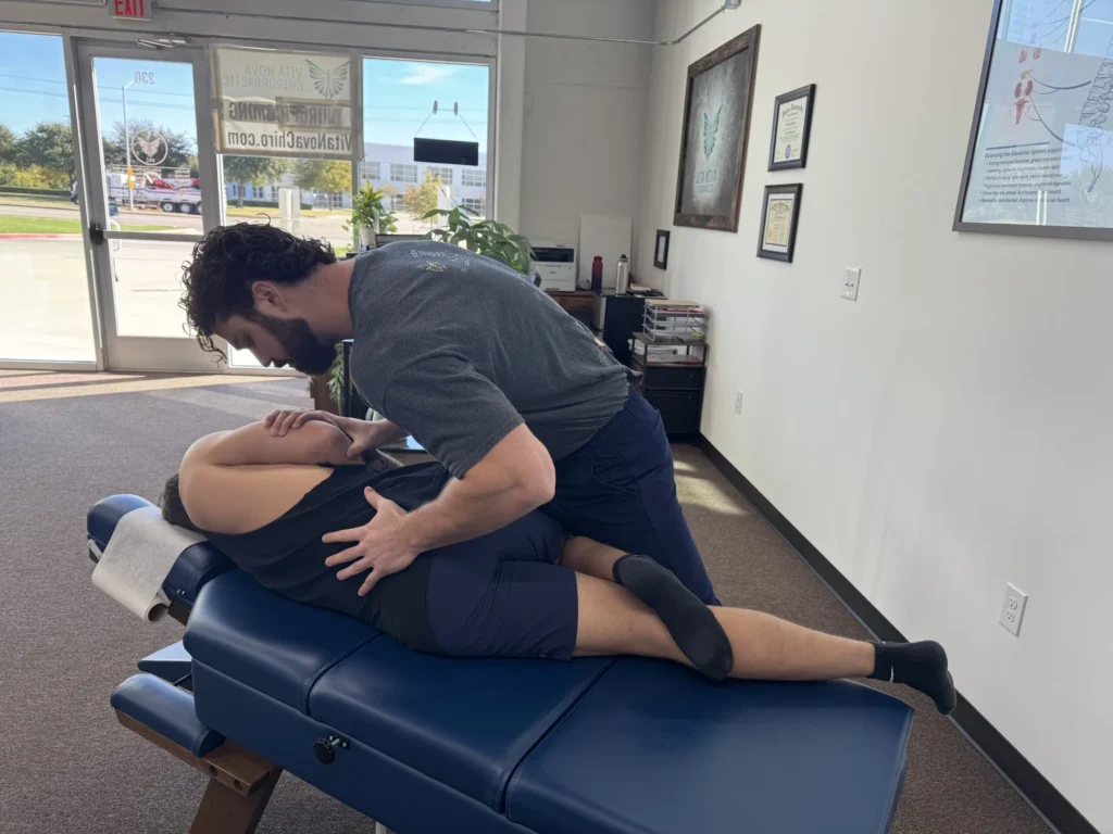 Dr. Korrin Taylor performs a side-posture chiropractic adjustment on a patient on a blue treatment table.